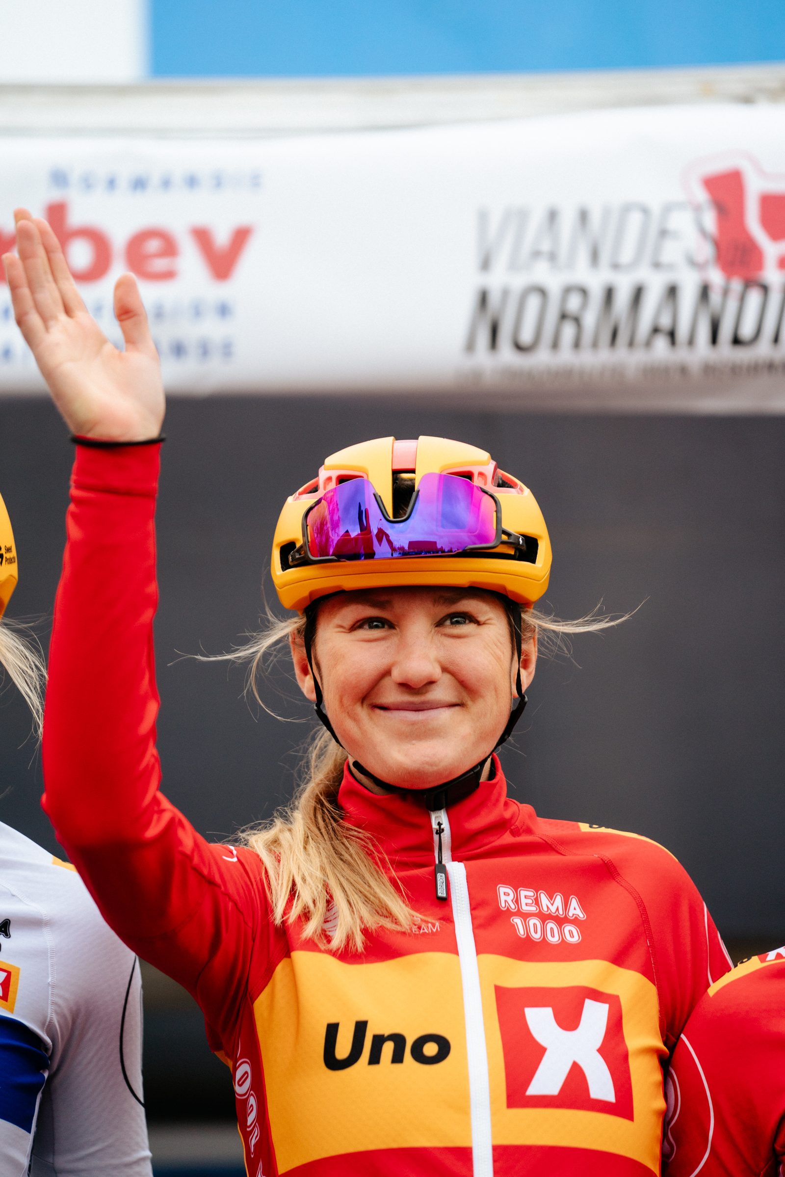 Joss Lowden waving on the podium after a stage of the Tour de Normandie